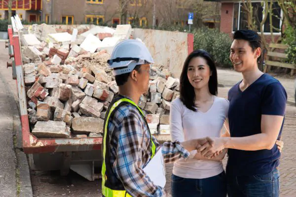 happy homeowner stand in front of dumpster contractor